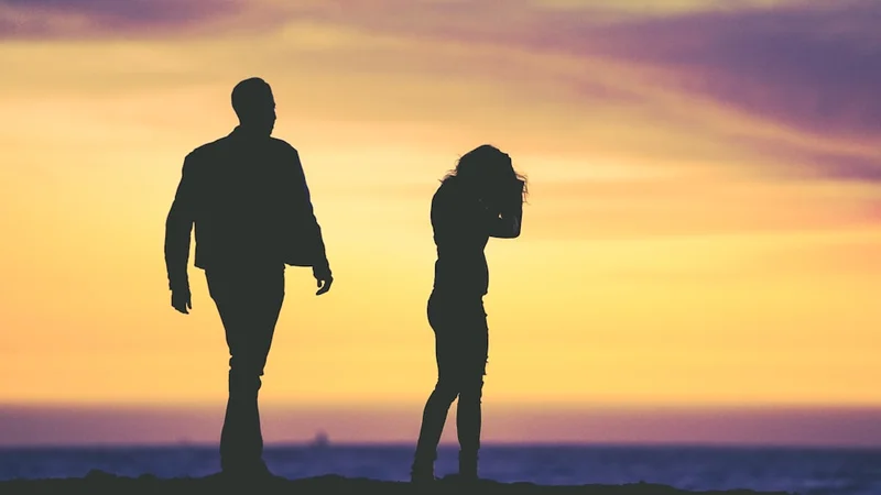 Two silhouettes facing each other across a narrow gap, soft warm backlight, editorial tone