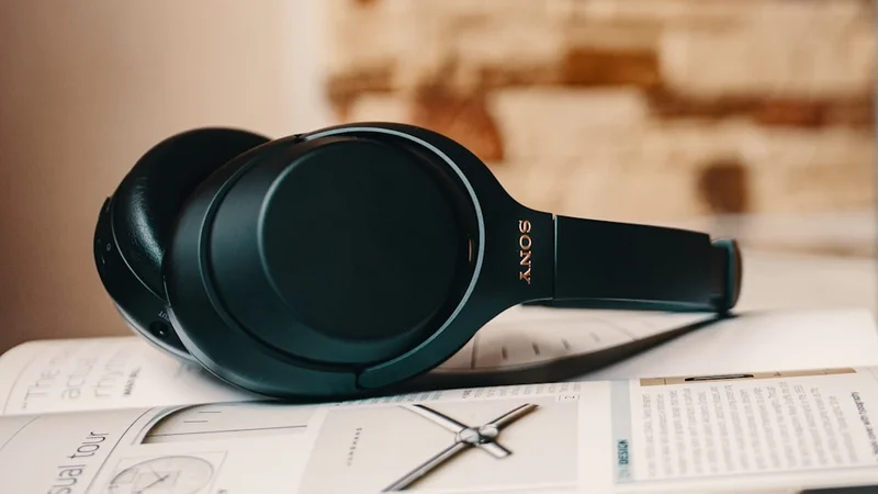Sony WH-1000XM5 noise-canceling headphones on minimalist desk beside laptop, clean editorial product shot