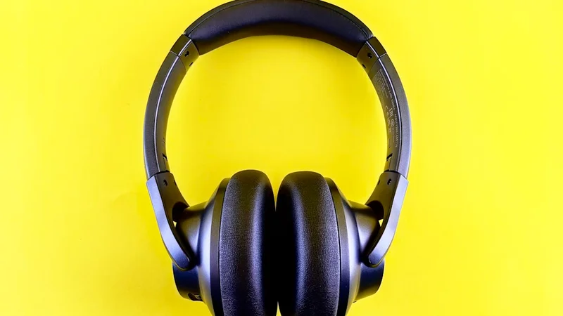 Affordable wireless headphones hanging on a monitor stand beside an open laptop in a tidy student desk setup