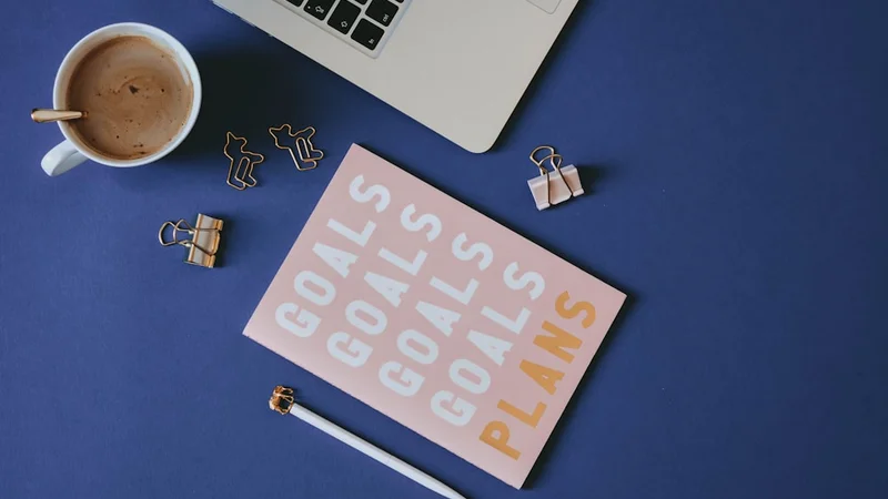 An open journal with handwritten notes next to a cup of coffee on a wooden table, morning light