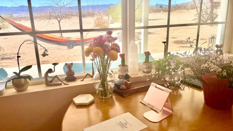 A person writing in an open gratitude journal at a wooden morning desk with a cup of coffee in soft natural light