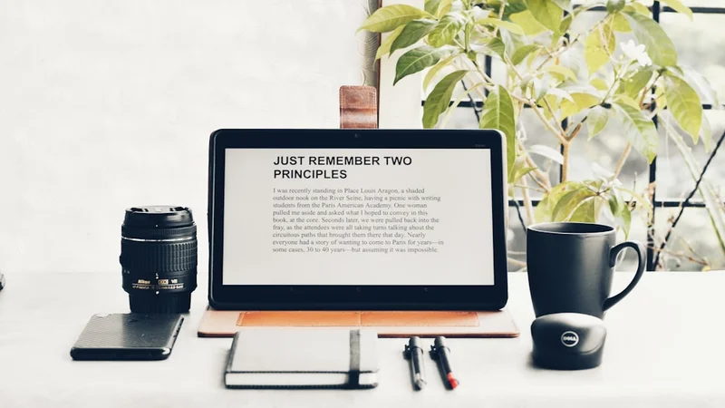 close-up of an analog watch on a wrist beside an open notebook and a coffee cup, clean desk with no phone visible