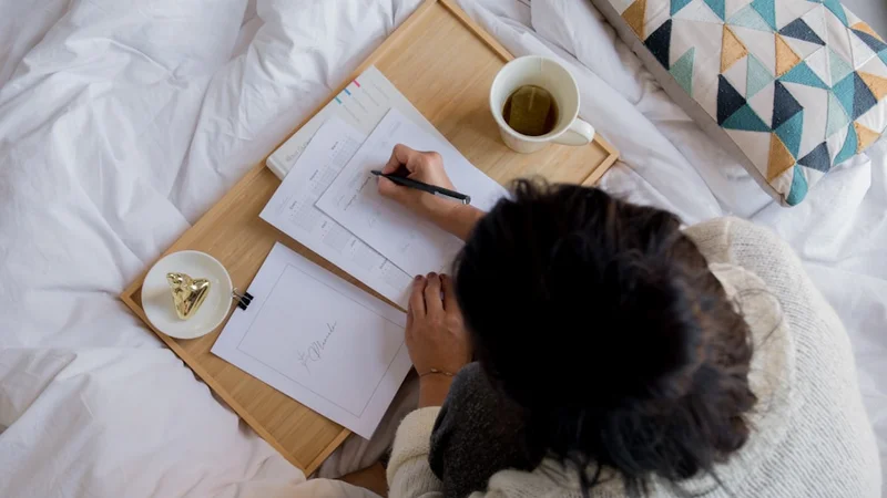 an early-morning desk with a hardcover learning journal open to a handwritten synthesis page, a physical book face-down beside it, and soft warm light — no screens