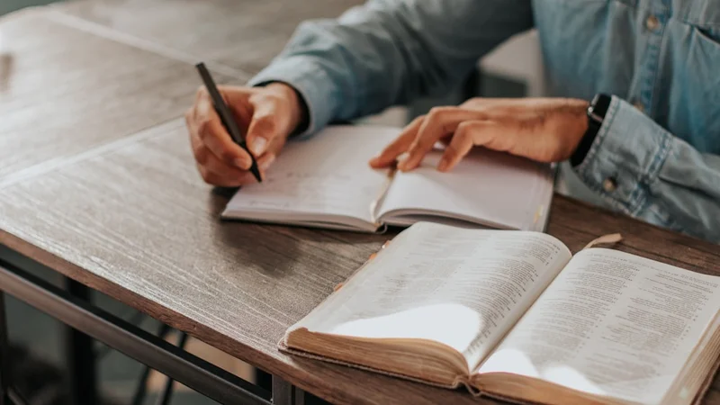 a person studying with handwritten annotations in a notebook next to a timer, focused and undistracted — no phone in sight