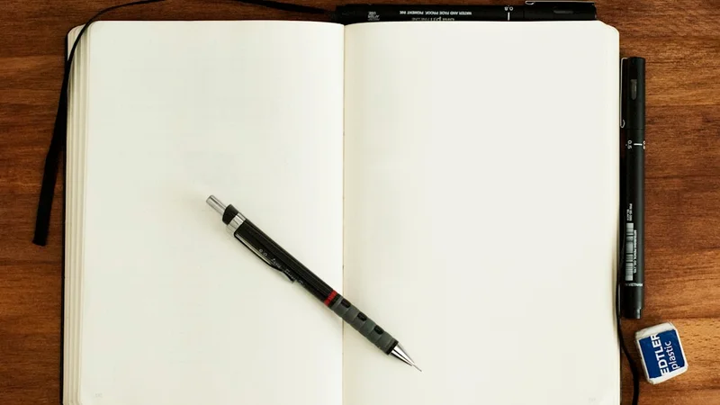 A small bedside notebook open with a short list and a pen resting across it, lit by a single warm lamp