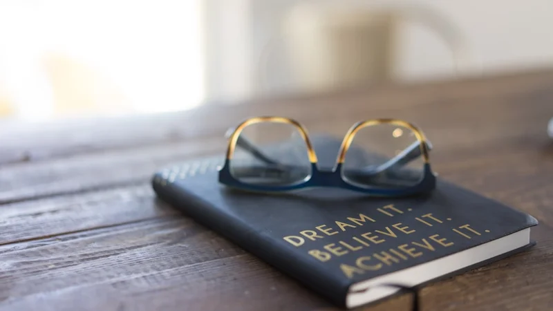 An open notebook with handwritten notes beside a warm lamp on a quiet desk at night, personal and unhurried