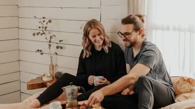 Two partners sitting across a candlelit dinner table with no phones visible, sharing a conversation and smiling