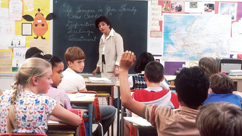 A warm classroom scene with a teacher leaning forward attentively toward a student, natural light, quiet and focused atmosphere