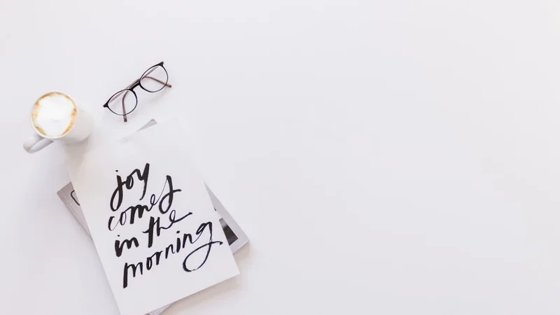 Minimal morning desk setup with an open structured journal, uncapped pen, and warm light