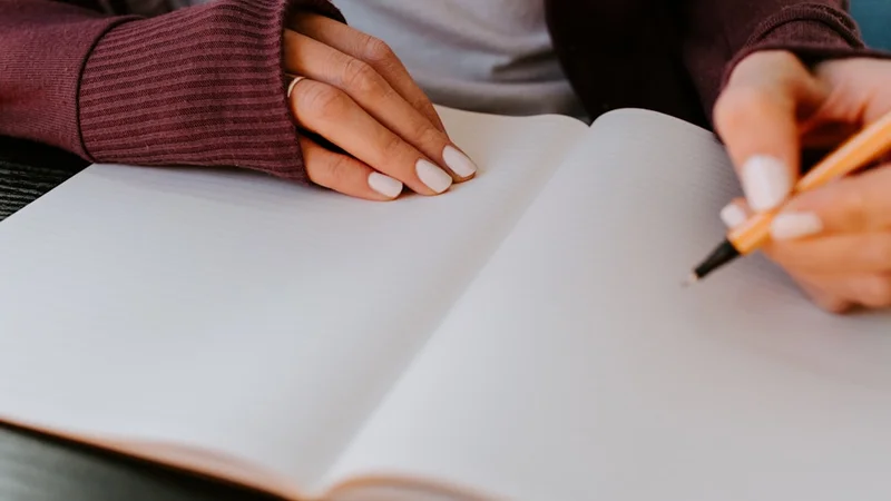 open journal on a wooden desk with brief handwritten notes in third-person perspective, coffee cup nearby, warm morning light