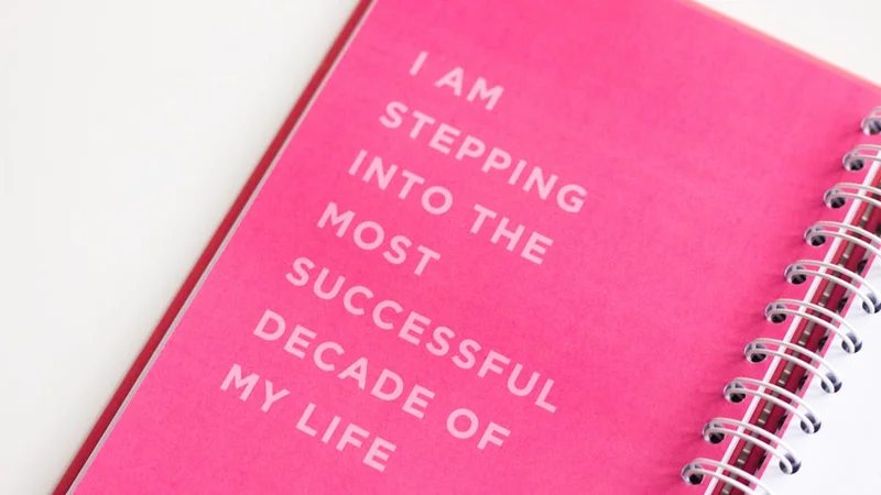 Open self-coaching journal with handwritten notes and questions beside a morning coffee