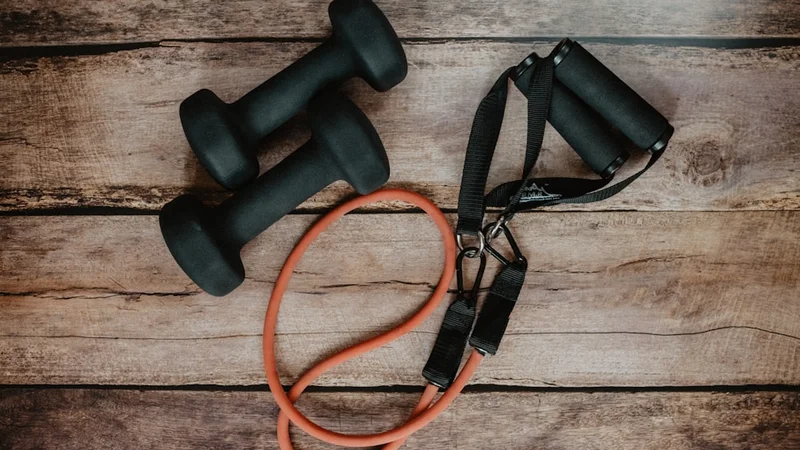 minimal workout setup with running shoes, a resistance band, and a small notebook on a wooden floor