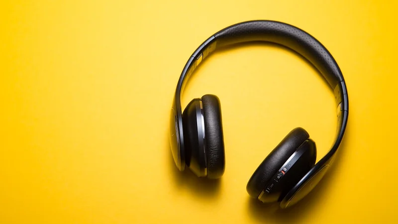 close-up of quality over-ear headphones resting on a wooden desk beside a small plant and a glass of water