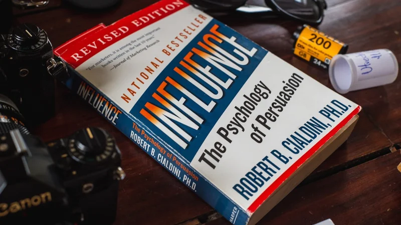 A person at a library table surrounded by open books and charts, brow furrowed in concentration — capturing the paradox of intelligence and entrenched belief
