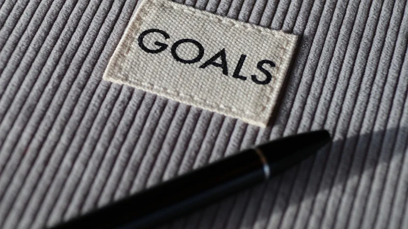 close-up of a hand circling a single written goal on a notebook page, surrounded by crossed-out alternatives