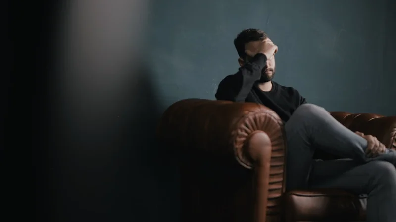 A person staring at a frozen phone screen, one hand resting on a coffee mug, shoulders slightly tense, clean minimal background