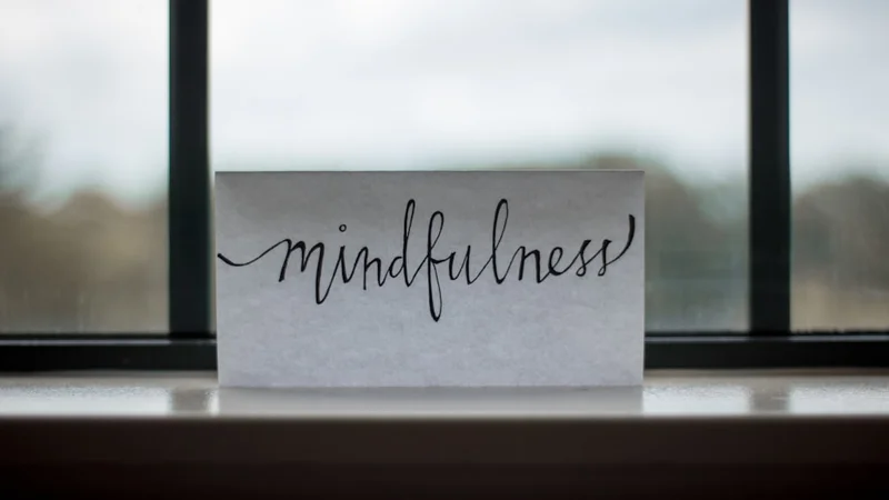 A person sitting calmly beside a window with a journal and a timer, focused and unhurried, natural morning light