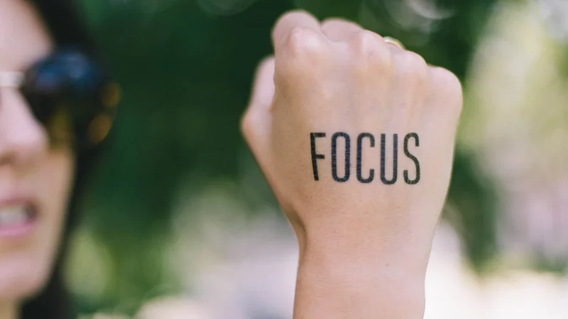 A close-up of focused hands engaged in skilled work — writing, typing, or holding a tool — suggesting absorbed process focus without outcome monitoring